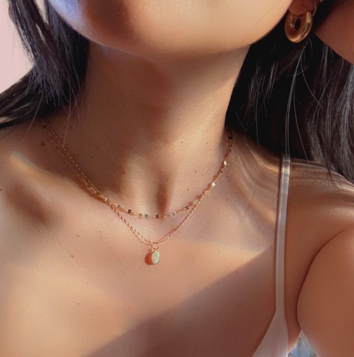 a girl wearing opal pendant necklace with 14k solid gold chain layered with other necklaces